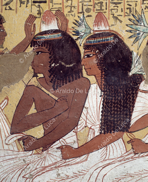 Detalle del registro inferior de la pared izquierda de la cámara funeraria. Sennedjem y su esposa sentados mientras reciben cuidados de su hijo, empeñado en arreglar el peinado de su padre.