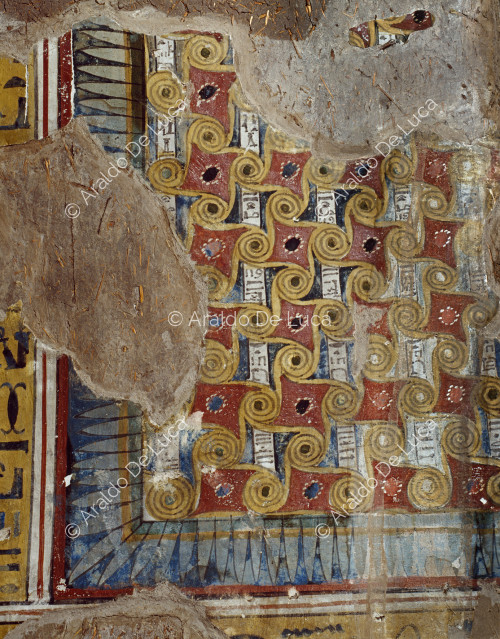 Detalle de la pintura del techo de la primera cámara de la tumba de Inherkau. Panel con decoración de volutas entrelazadas entre las que pasan hileras de jeroglíficos sobre fondo blanco.