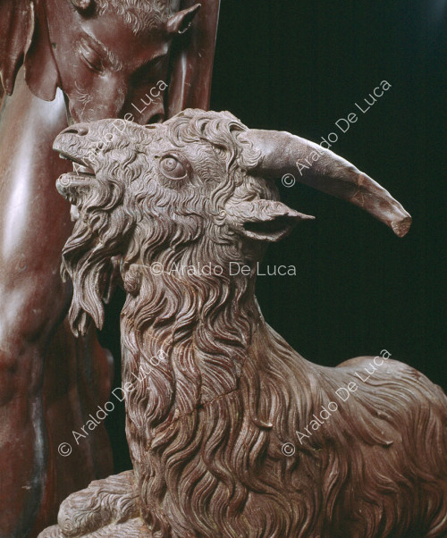 Statue of drunken Faun in antique red. Detail with goat